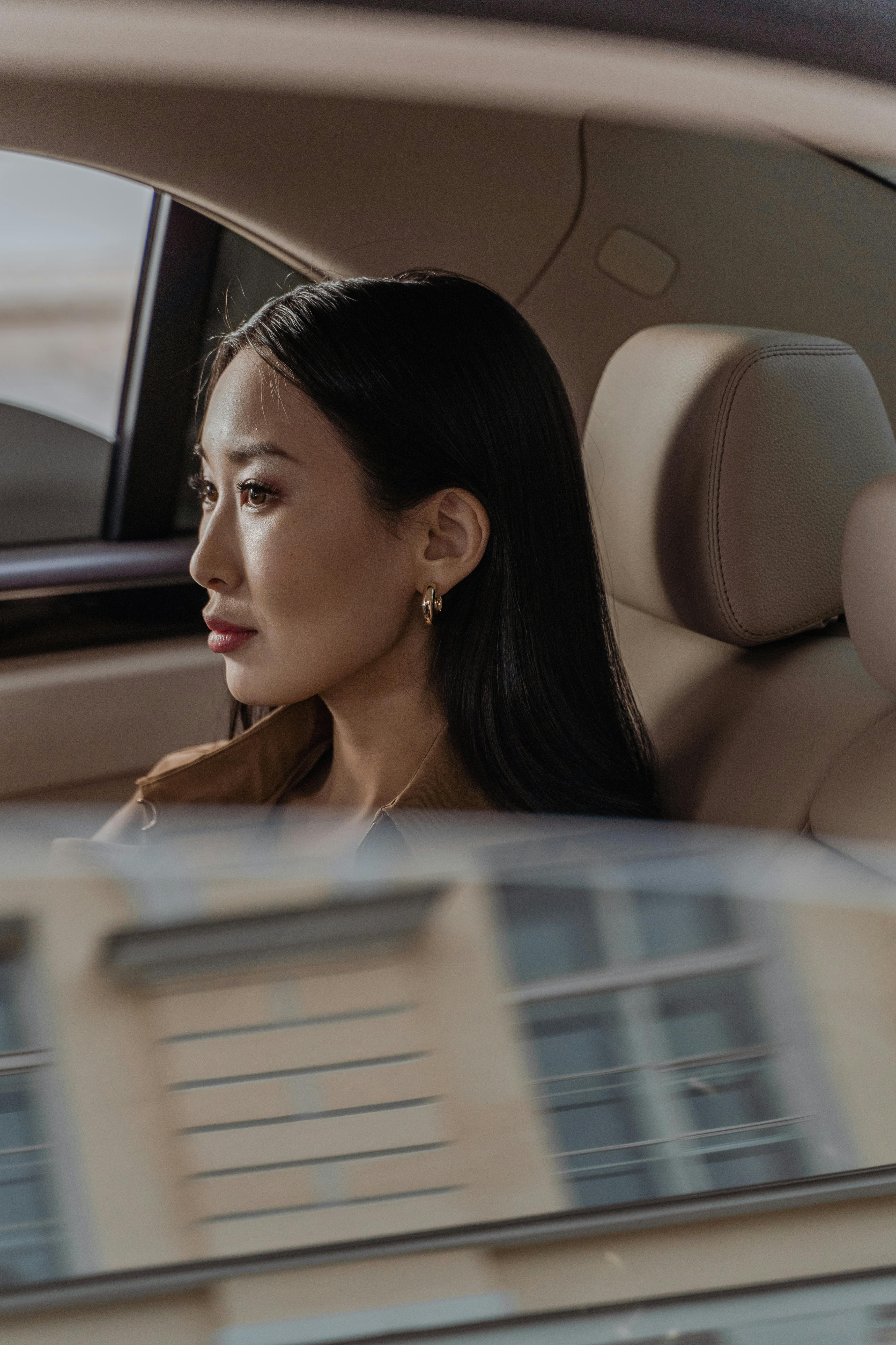 Woman sitting quietly in a car, looking out the window